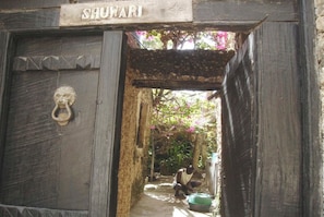 A wooden door with a lion head knocker and the name 'SHUWARI' above it. - New Listing (Lamu)
