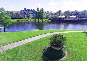 A well-maintained grassy area with a curved pathway leading to a body of water, surrounded by buildings with a uniform architectural style. - Spacious 3 Bedroom 4 miles to Disney Great Resort (Kissimmee)