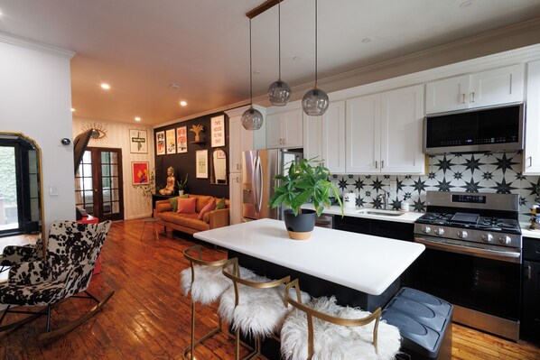 A modern kitchen with white cabinets, a stainless steel refrigerator, a black microwave, and a gas stove. - Stylish Brooklyn 1-bedroom apartment with Private Backyard (Brooklyn)
