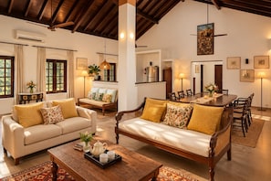 A spacious living area with a sofa set, a dining table, and a coffee table. - Raht Aashyana Lakhanpal Goa (Candolim)