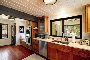 Een moderne keuken met houten kastjes, roestvrijstalen apparatuur en een groot raam met uitzicht op het omliggende landschap.