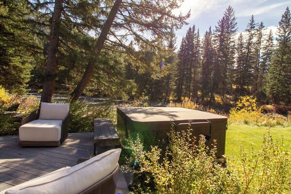 A deck with outdoor furniture and a storage unit in a forested area. - The Gallatin Riverstead (Big Sky)