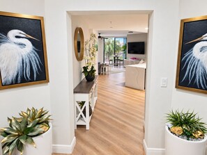 A modern interior with a wooden floor, a dining area with a round table, and a kitchen with a TV. - Cape Harbour Marina Condo with Huge Private Veranda (Cape Coral)