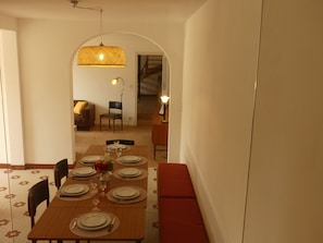 A dining area with a long table set for four, a bench along one wall, and a doorway leading to another room. - New Listing (Marnes 79600)