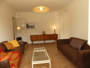 A living room with two sofas, a coffee table, a cabinet, and a hanging light fixture. - New Listing (Marnes 79600)