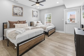 A bedroom with two beds, a ceiling fan, and a door with a view. - Entire 6BR Duplex near Downtown Indy, Sleeps 15 (Indianapolis)