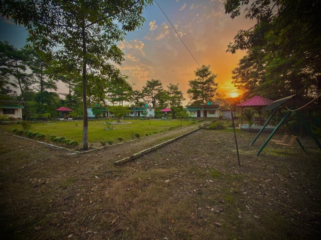Un patio con parque infantil, árboles y edificios con tejados rojos.