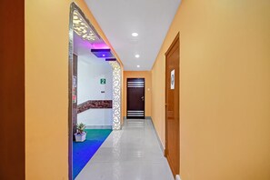A hotel corridor with a reception desk, a blue carpet, and a wooden door. - Hotel O Tower Shanavi Inn (Barasat)