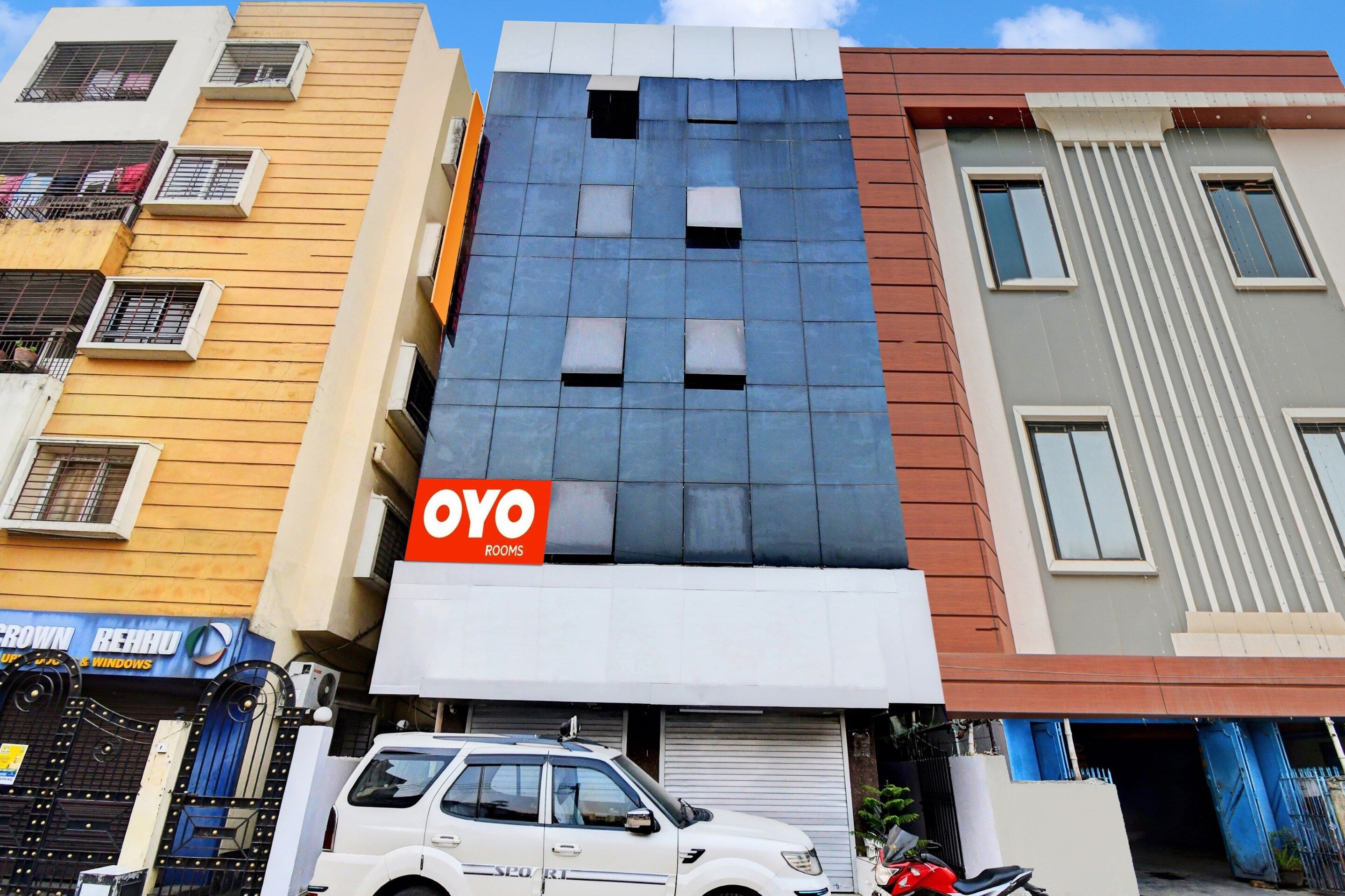 Un edificio de varios pisos con un llamativo letrero de 'OYO ROOMS'.