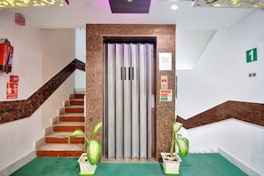 A hotel entrance with a staircase, a lift, and emergency signage. - Hotel O Tower Shanavi Inn (Barasat)