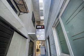 Un couloir étroit, sur lequel est apposée une enseigne indiquant l’hôtel OYO Hotel Royal Inn, et qui signale la possibilité de réserver une chambre de luxe.