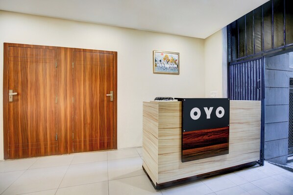 A reception desk with a sign reading 'OYO' in a modern interior with wooden doors and a framed picture on the wall.