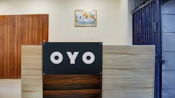 A sign with the word 'OYO' on a wooden panel, a wooden door, a framed picture on the wall, and a metal gate.