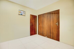 A hallway with two wooden doors, a tiled floor, and a framed picture on the wall.