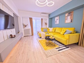 A modern living room with a yellow sofa, a flat-screen TV, and a coffee table. - Spacious Luxurious Central 4-bedroom apartment in Bucuresti next to Old Town (București)