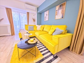 A modern living room with a bright yellow sofa, a glass coffee table, and a striped rug. - Spacious Luxurious Central 4-bedroom apartment in Bucuresti next to Old Town (București)