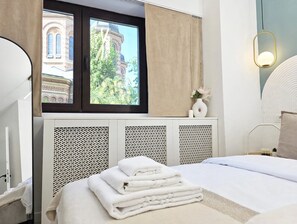 A hotel room with a bed, a window with curtains, a radiator, and a wall-mounted light fixture. - Spacious Luxurious Central 4-bedroom apartment in Bucuresti next to Old Town (București)