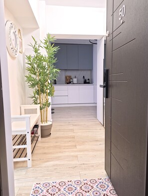A modern kitchen with white cabinets, a bamboo plant, and a wooden bench. - Spacious Luxurious Central 4-bedroom apartment in Bucuresti next to Old Town (București)