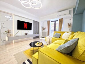 A modern living room with a yellow sofa, a flat-screen TV, and a minimalist design. - Spacious Luxurious Central 4-bedroom apartment in Bucuresti next to Old Town (București)