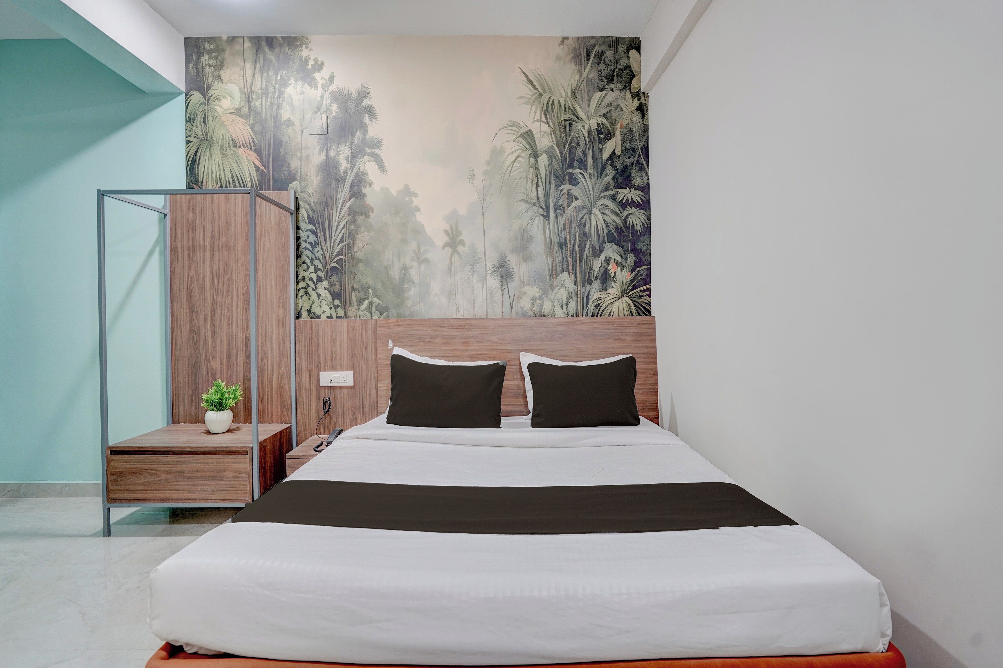 Un dormitorio con cama, mesita de noche, lámpara y un mural en la pared.