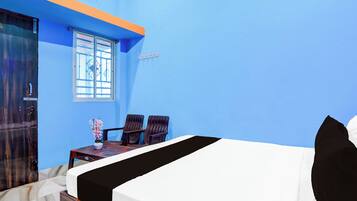 A room with a bed, two chairs, a small table, and a window.