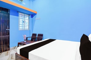 A room with a bed, two chairs, a small table, and a window. - Hotel O Elegant Stay CDA (Cuttack)