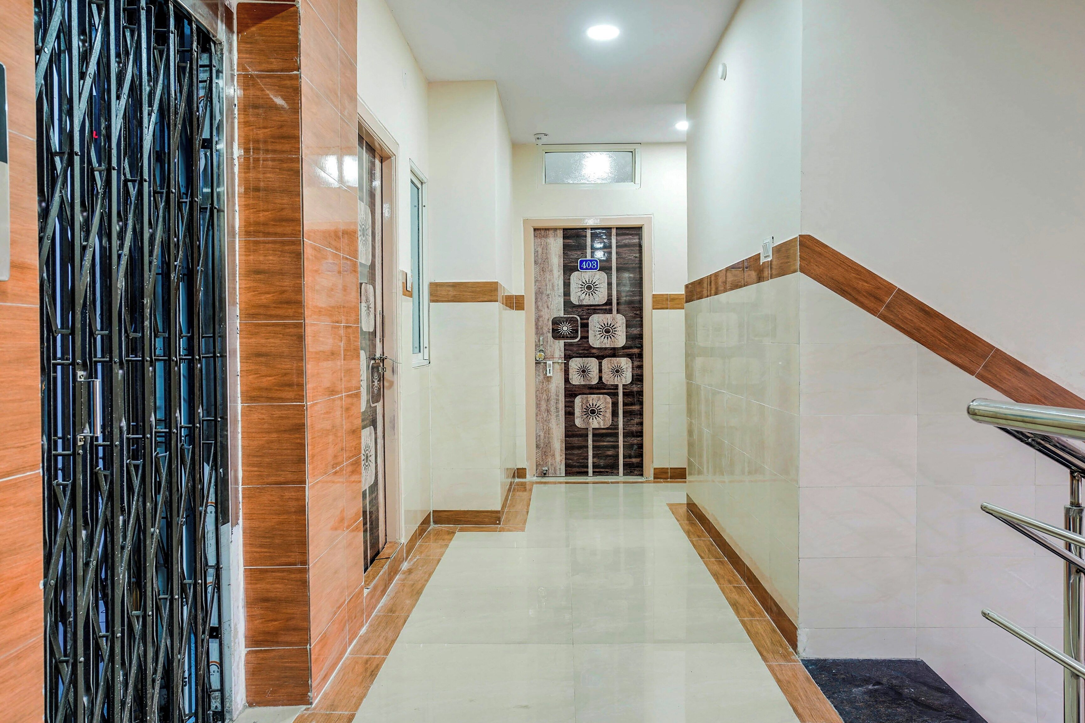 Un pasillo con una reja metálica, paredes de azulejos y una escalera con barandilla.