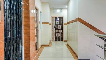 Un pasillo con una reja metálica, paredes de azulejos y una escalera con barandilla.