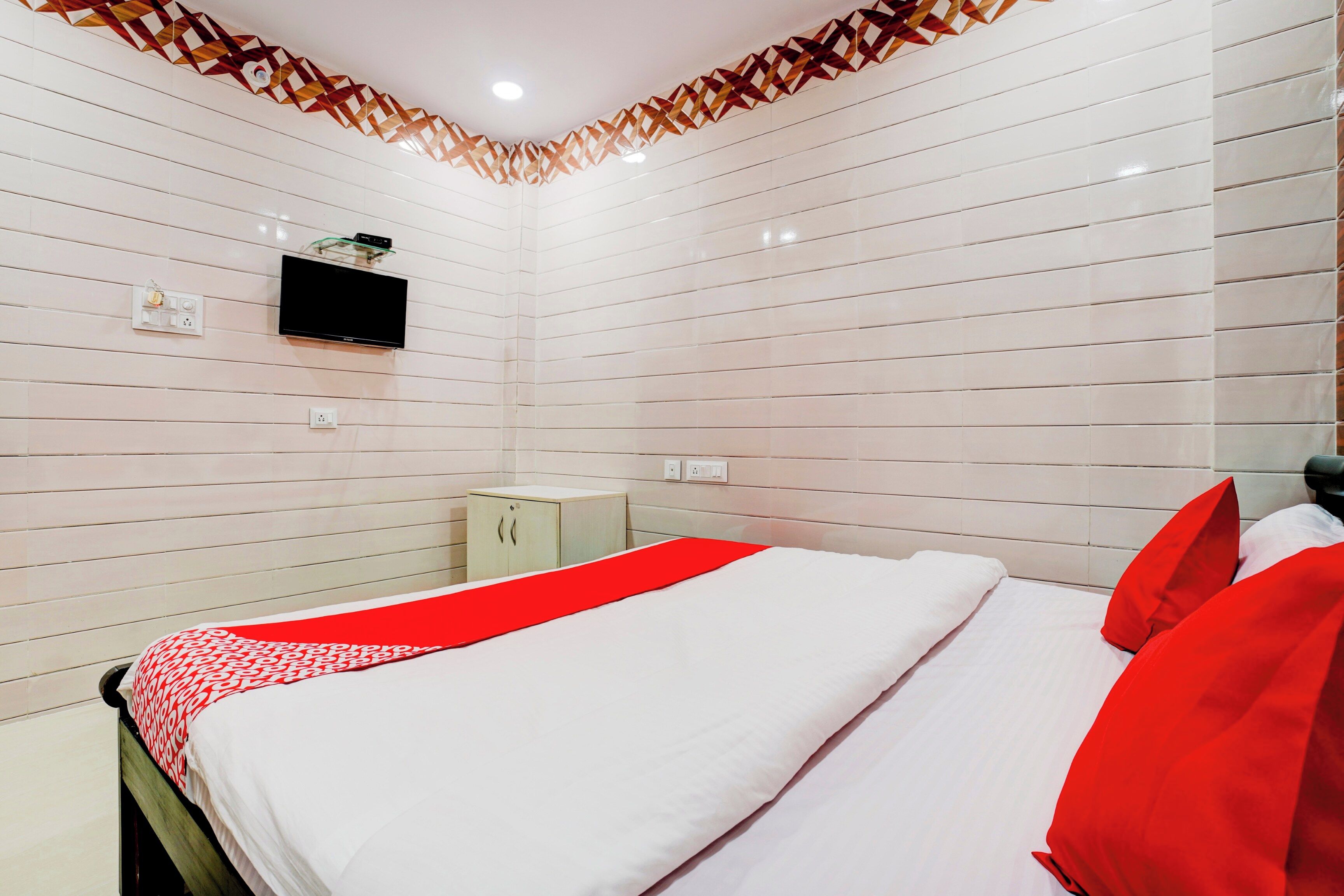 Una habitación de hotel con una cama, un televisor montado en la pared y un mueble pequeño.