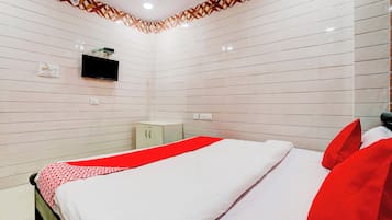 Una habitación de hotel con una cama, un televisor montado en la pared y un mueble pequeño.