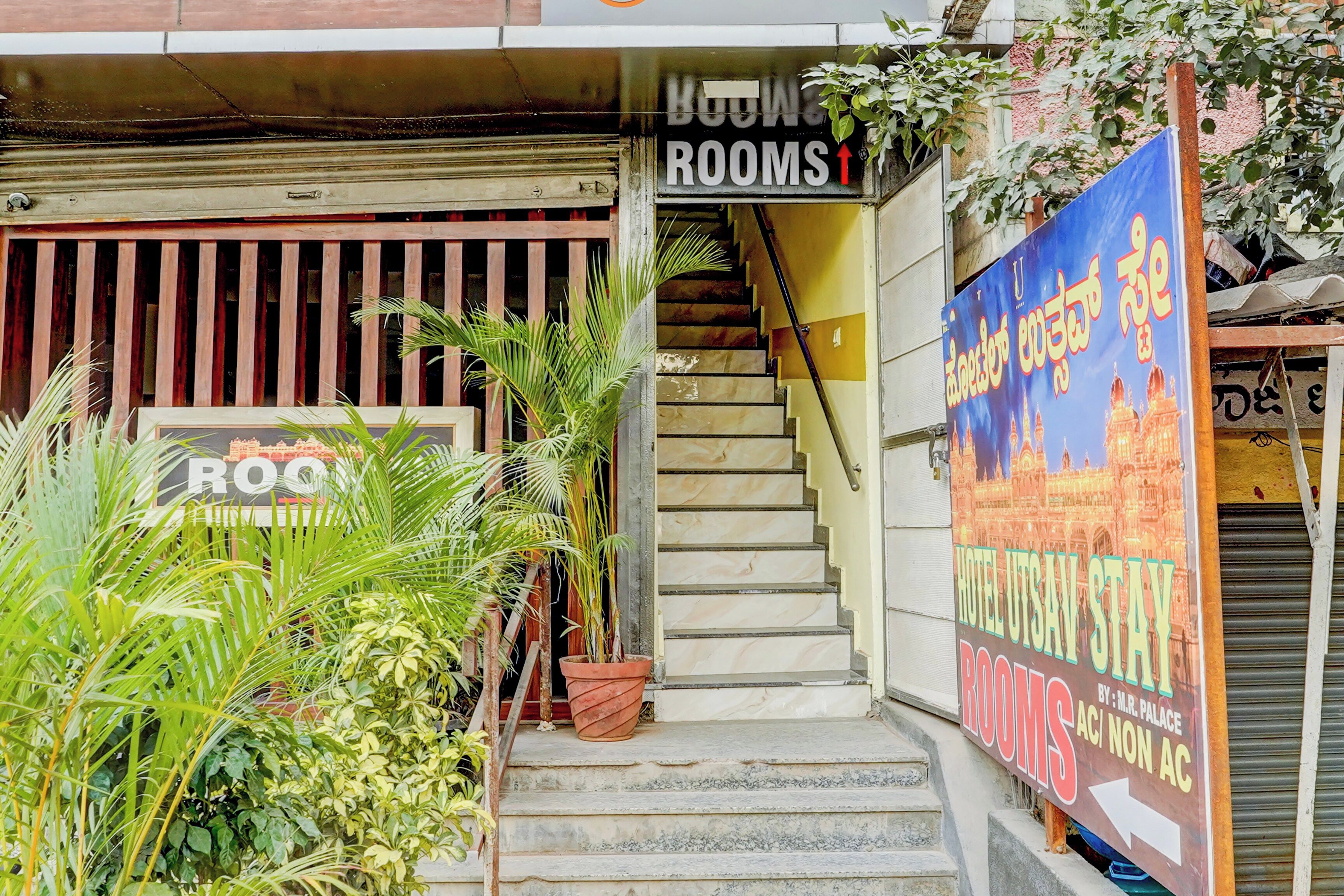 A hotel entrance with a staircase leading to rooms, a sign for 'Hotel Utsai Sway,' and a sign for 'Rooms.'