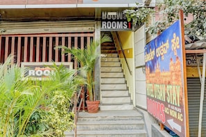 Entrada d'un hotel amb una escala que condueix a les habitacions, un rètol que diu 'Hotel Utsai Sway' i un altre que indica 'Habitacions'.