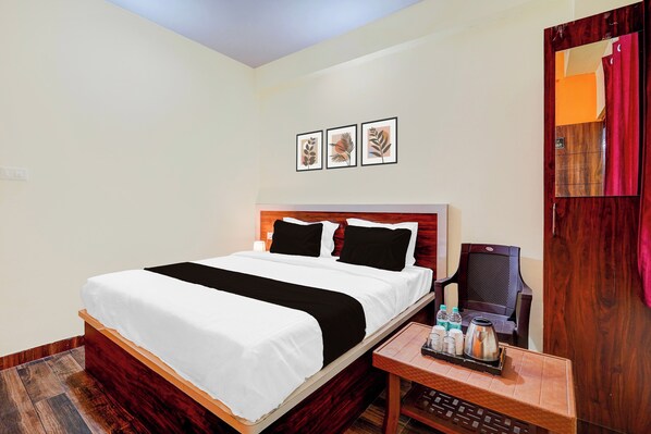 A hotel room with a bed, a nightstand with a kettle, and a mirror with curtains. - Hotel O Utsav Stay Nagarbhavi (Bangalore)