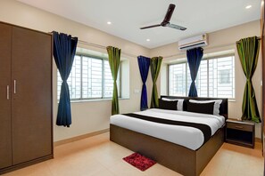 A hotel room with a bed, a wardrobe, a nightstand, an air conditioning unit, and curtains. - Hotel O Newtown worldstay (Kolkata)