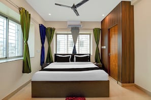 A hotel room with a bed, curtains, a ceiling fan, an air conditioning unit, and a view through the window. - Hotel O Newtown worldstay (Kolkata)