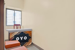 Um quarto pequeno com janela, uma cadeira e um balcão com um aviso.