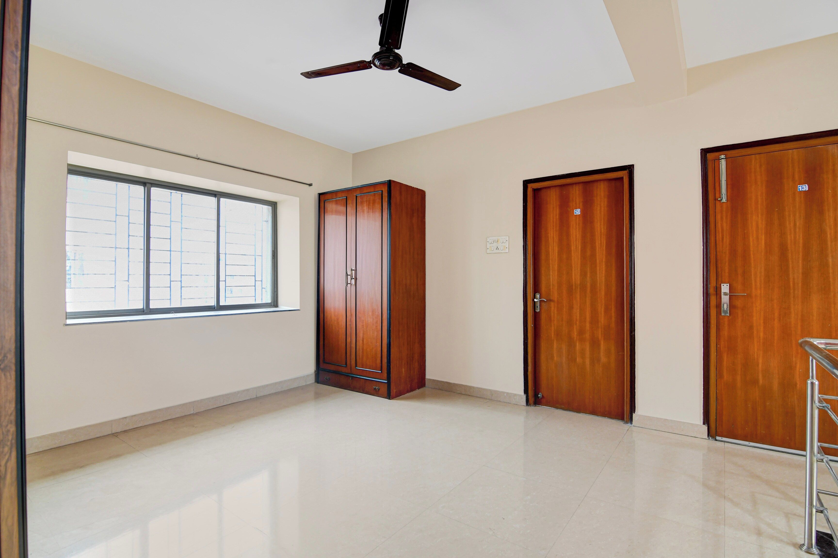 Una habitación con un ventanal grande, un ventilador de techo y dos puertas de madera.