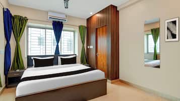 Quarto de hotel moderno com uma cama grande, um ventilador de teto, ar condicionado e uma janela com cortinas.