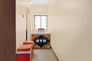 Um corredor estreito com uma janela, um banco e um balcão com uma placa.