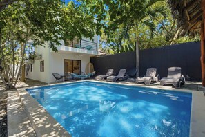 A swimming pool with lounge chairs and a building with a balcony. - Private Villa with pool and BBQ (Potrero)