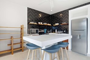 A modern kitchen with a central island, bar stools, a microwave, and a refrigerator. - Private Villa with pool and BBQ (Potrero)