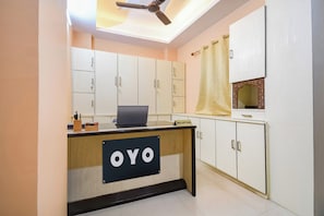 A reception desk with a sign reading 'OYO' in a hotel lobby with white cabinets and a ceiling fan. - Hotel O MOHAR KUNJHA (Barasat)