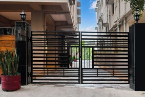 A gated entrance with a metal gate, potted plants, and a building facade in the background. - Hotel O MOHAR KUNJHA (Barasat)