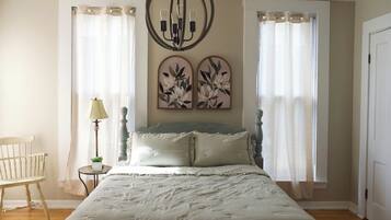 Een slaapkamer met een bed, een stoel, een lamp en twee wanddecoraties.