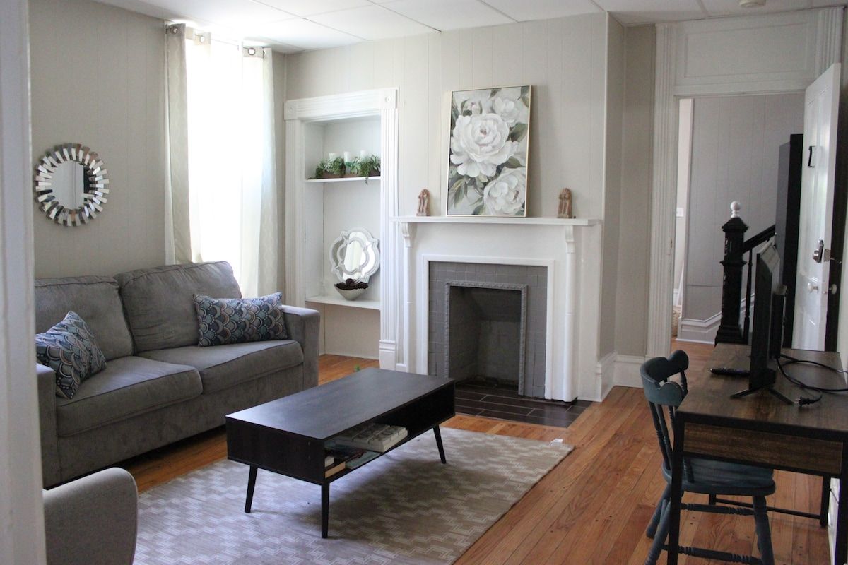 A living room with a fireplace, a sofa, a coffee table, and a dining table with chairs.