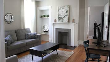 A living room with a fireplace, a sofa, a coffee table, and a dining table with chairs.