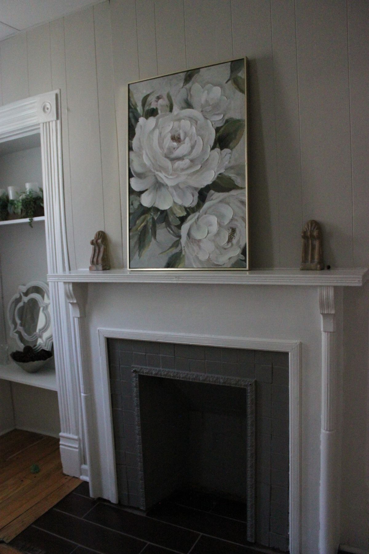 Een open haard met een bovenplaat, begrensd door witte wanden en een houten vloer.