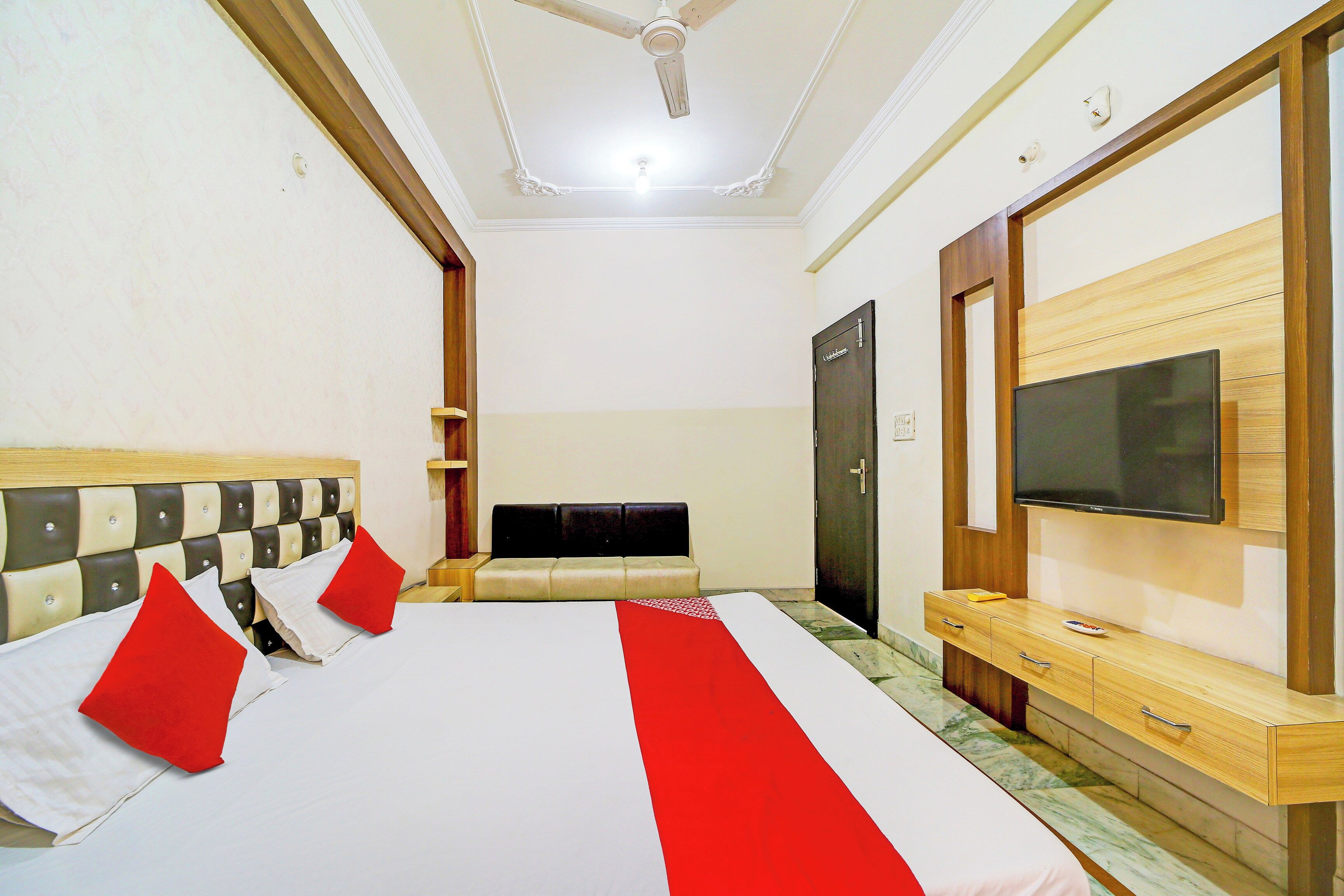 A hotel room with a large bed, a television, a wardrobe, and a ceiling fan.