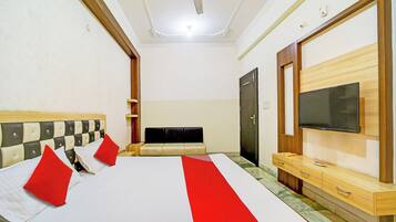 A hotel room with a large bed, a television, a wardrobe, and a ceiling fan.