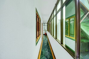 Un pasillo con ventanas amplias a ambos lados, una planta en maceta y un letrero en la pared.